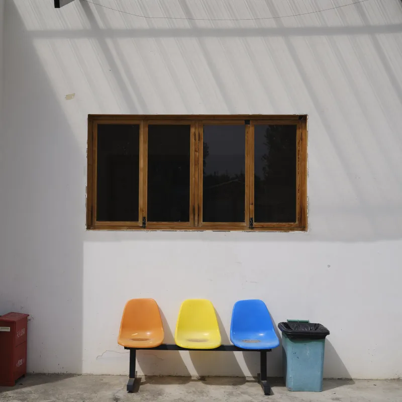 Orange, yellow and blue seats under a wooden window at the Studio Phantasm space